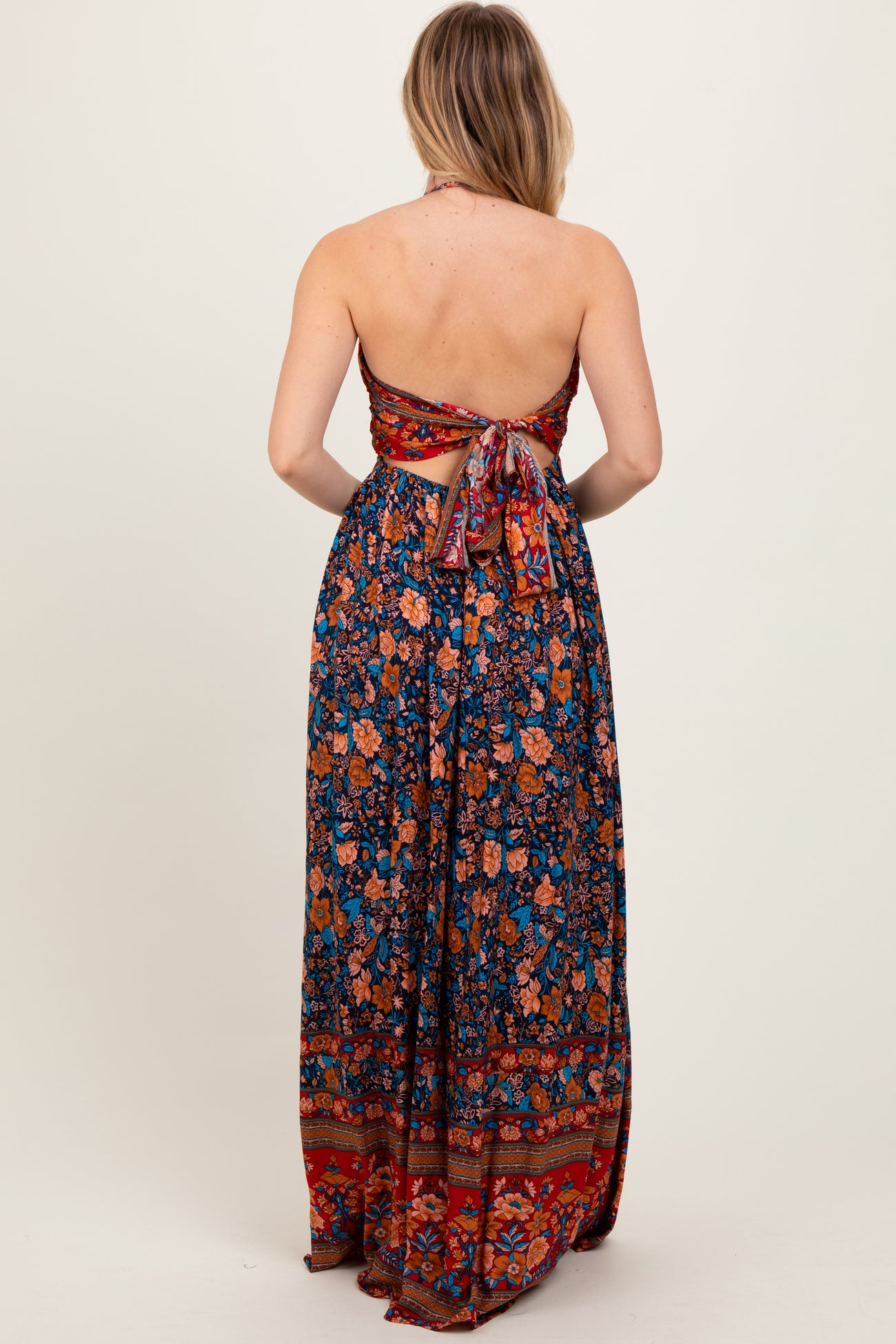 woman wearing a floral print strapless maxi dress with a tie back, featuring vibrant colors and intricate patterns