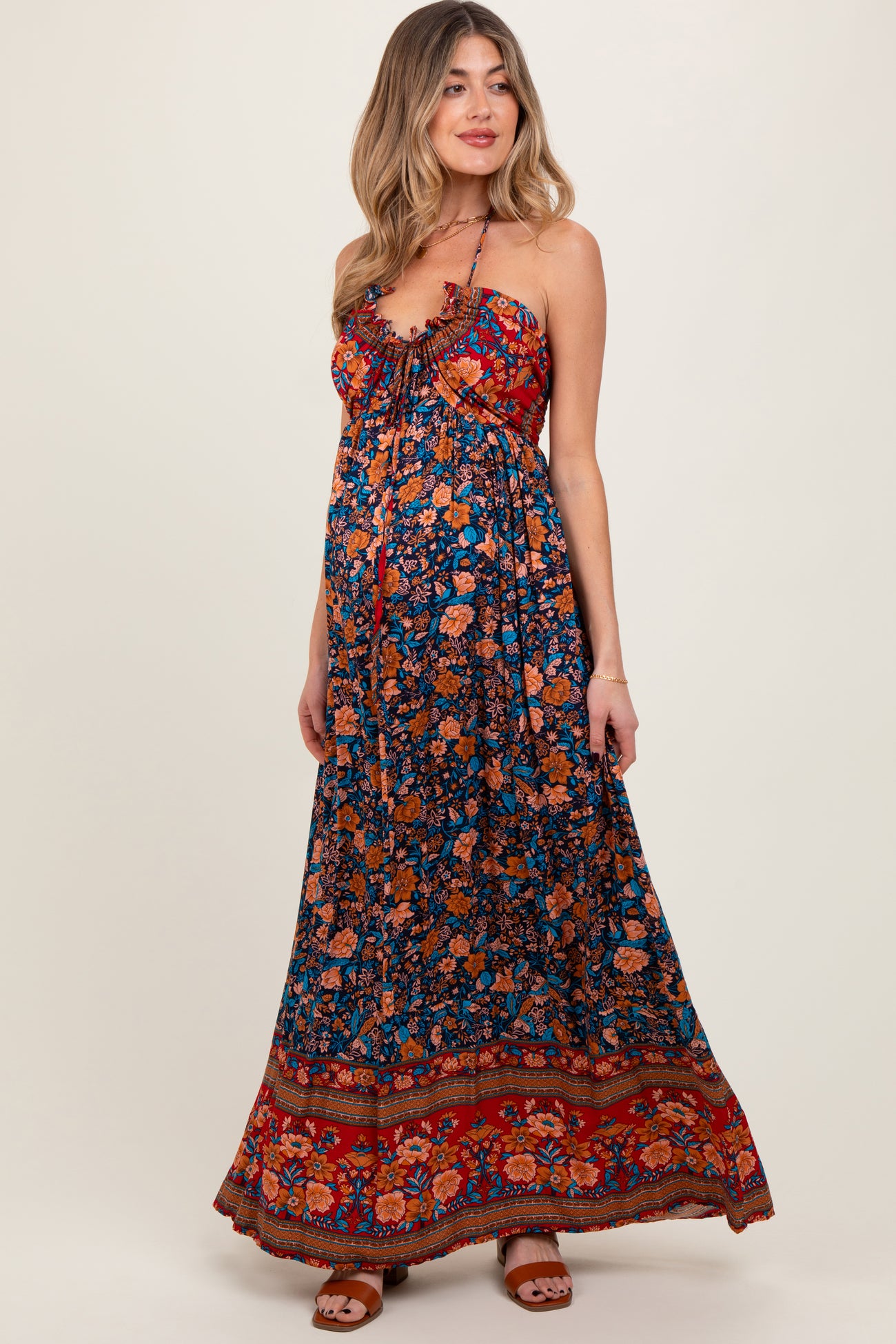 woman wearing a floral print maxi maternity dress with a halter neckline and a visible baby bump