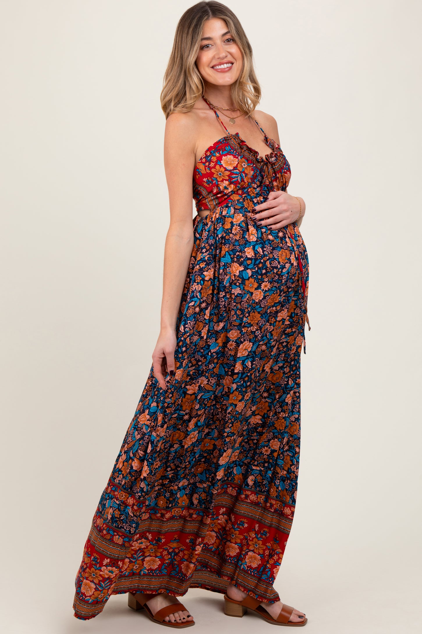 woman wearing a floral strapless maternity maxi dress and holding her baby bump