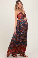 woman wearing a floral strapless maternity maxi dress and holding her baby bump