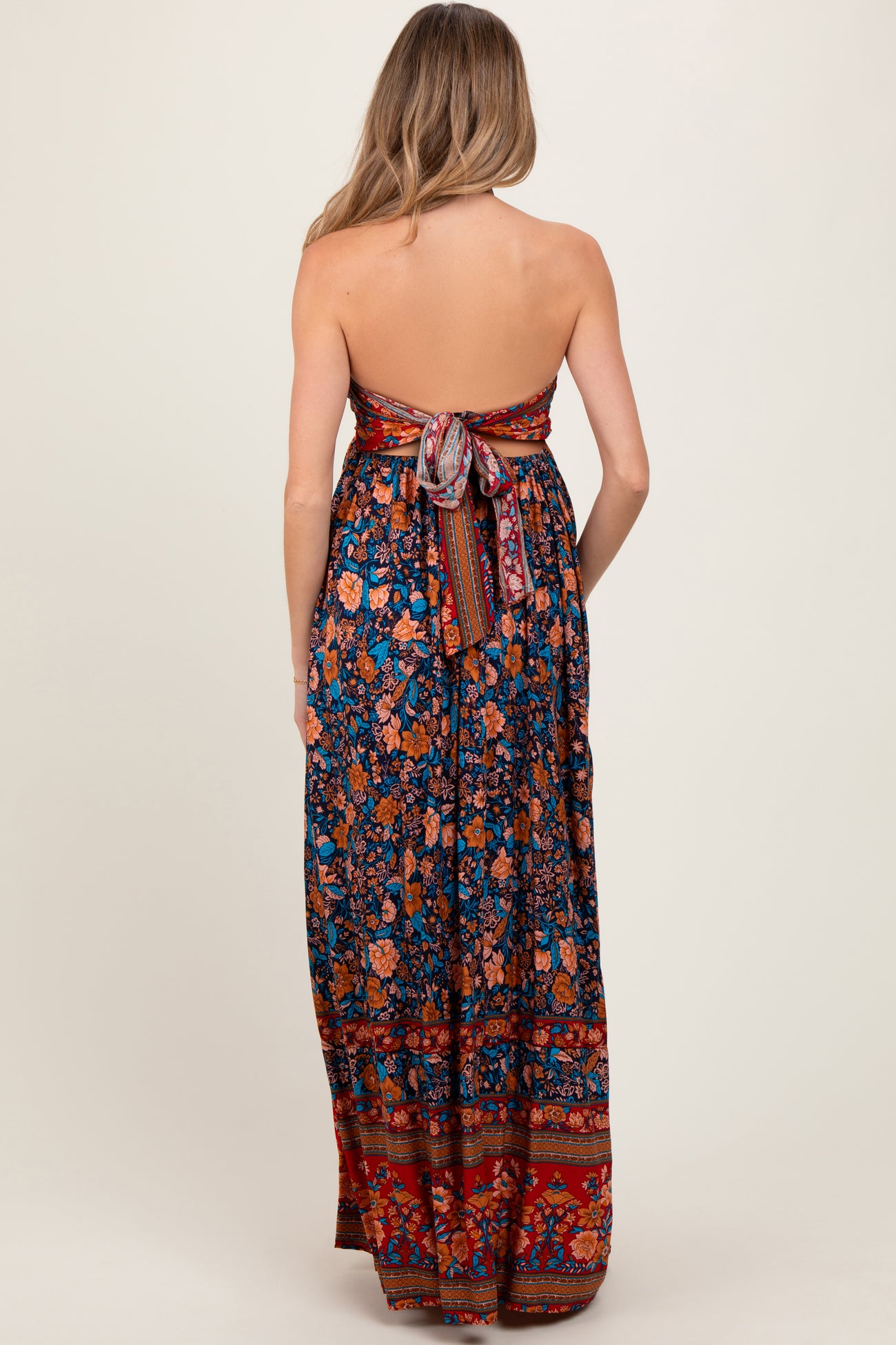 woman wearing a floral strapless maternity maxi dress with a tie back detail and flowing skirt