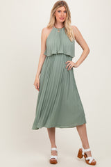 woman wearing a sage green pleated maxi dress with a halter neckline and layered bodice