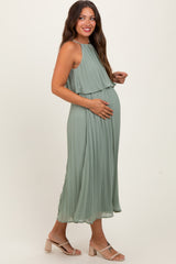 woman wearing a light green pleated maternity dress and holding her baby bump