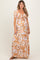 woman wearing a floral print maternity maxi dress with puff sleeves and a tied front detail, showcasing her baby bump