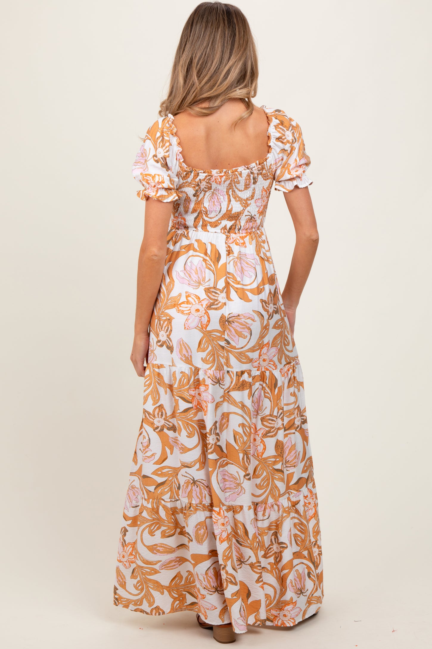 woman wearing a floral print maternity maxi dress with puff sleeves, seen from the back