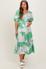 woman wearing a green floral maternity dress with puffed sleeves and a baby bump visible
