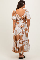 woman wearing a brown floral print maternity maxi dress with puff sleeves and open back detail