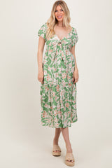 woman wearing a green floral midi dress with a tie front and puff sleeves, standing and smiling