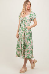 woman wearing a green floral midi dress with puff sleeves and tied front, paired with woven platform sandals