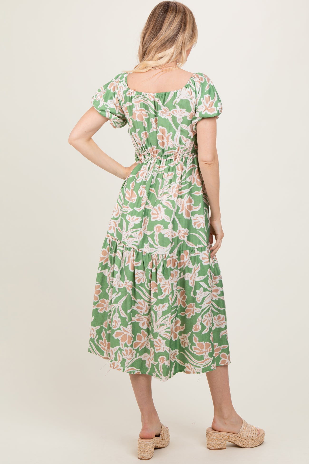 woman wearing a green floral maxi dress with puff sleeves and a fitted waistband, showing the back view