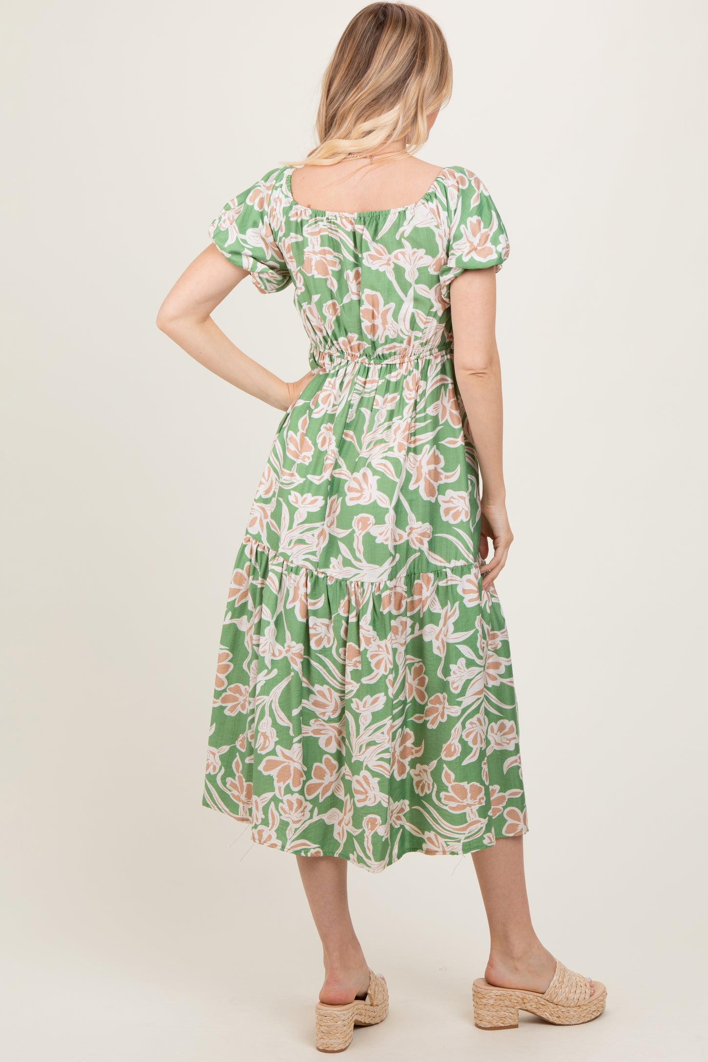 woman wearing a green floral maxi dress with puff sleeves and a fitted waistband, showing the back view