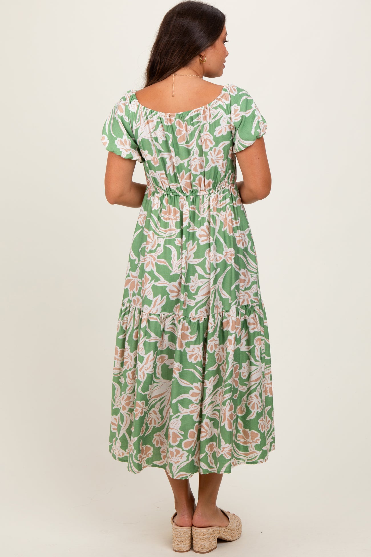 woman wearing a green floral maternity maxi dress with an elastic waist and short sleeves, showing her baby bump