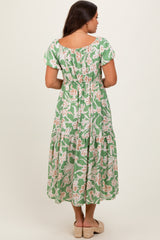 woman wearing a green floral maternity maxi dress with an elastic waist and short sleeves, showing her baby bump