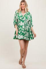 woman wearing a green floral mini dress with a v-neck and tiered skirt, standing and smiling
