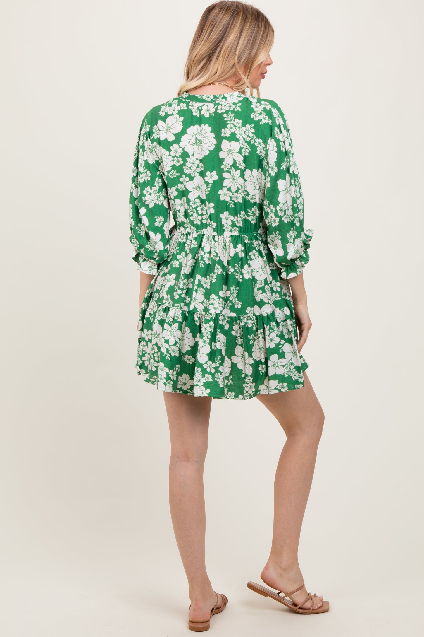 woman wearing a green floral print dress with three-quarter sleeves and a flared skirt, shown from the back