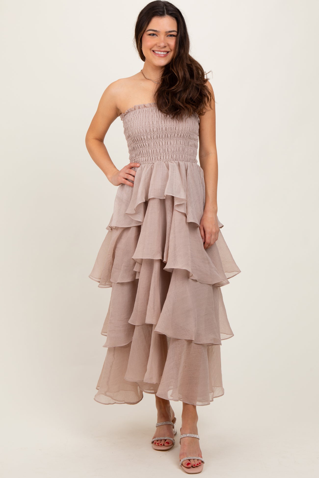 woman wearing a strapless nude tiered maxi dress with a smocked bodice and wavy ruffles