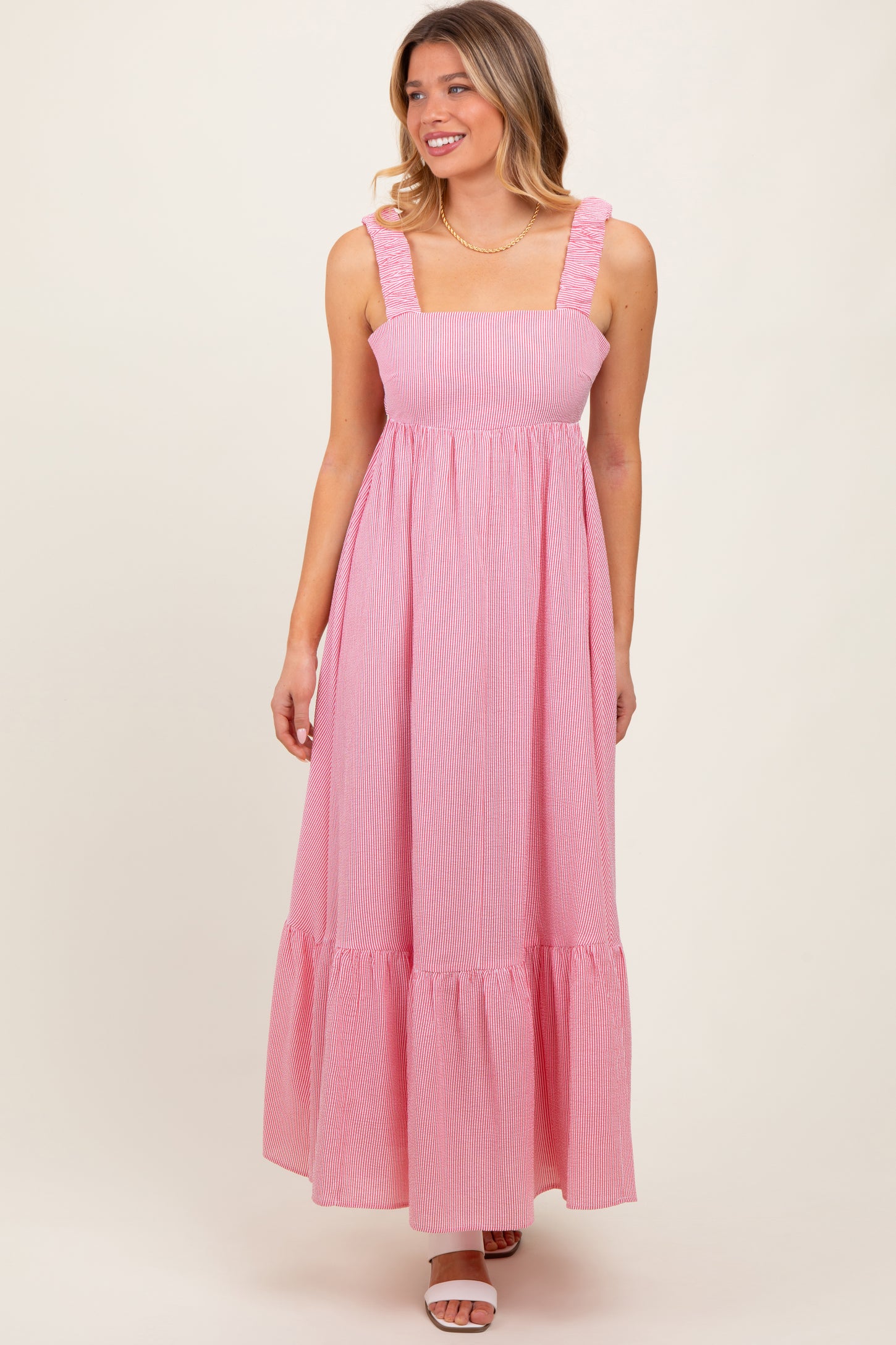 woman wearing a pink and white striped maxi dress with ruffled straps and a tiered skirt