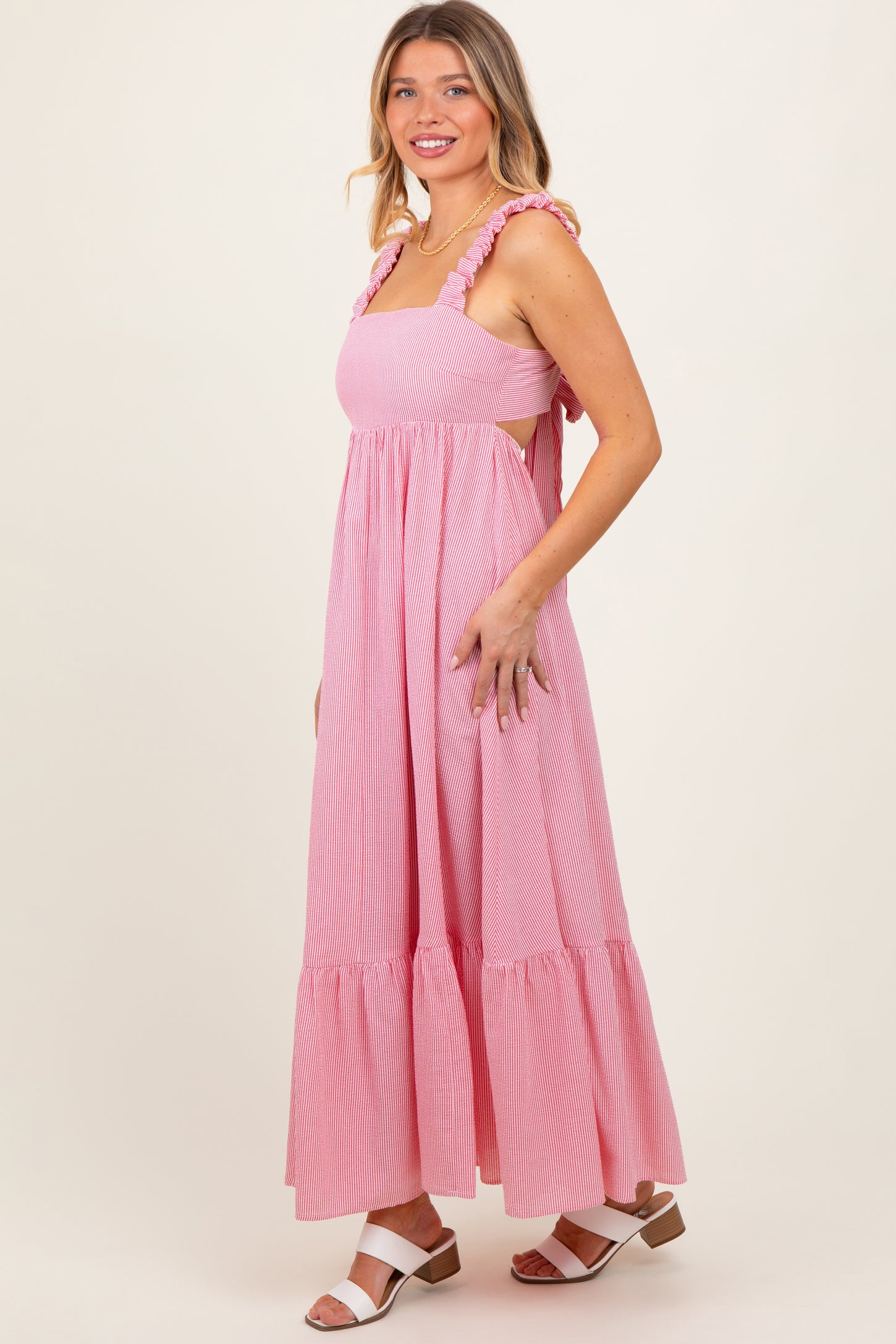 woman wearing a pink and white striped maxi dress with ruffle straps and a tiered skirt