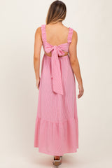 woman wearing a pink and white striped maxi dress with ruffled sleeves and a tie-back detail