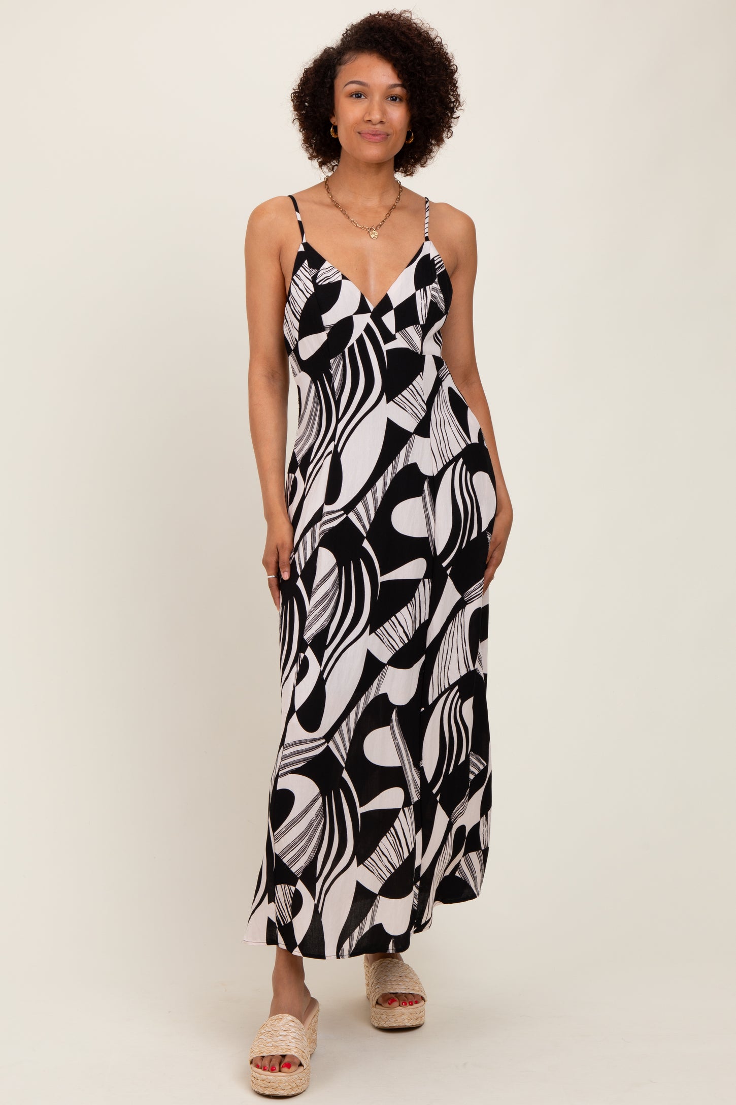 woman wearing a black and white patterned maxi dress with thin straps and a v-neckline