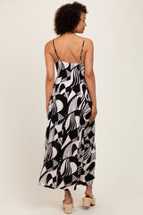 woman wearing a black and white patterned maxi dress with thin straps, showing the back view and styled with platform shoes