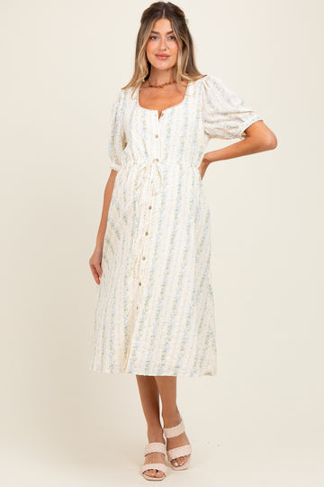 woman wearing a cream floral maternity midi dress with puff sleeves and button front, showcasing her baby bump
