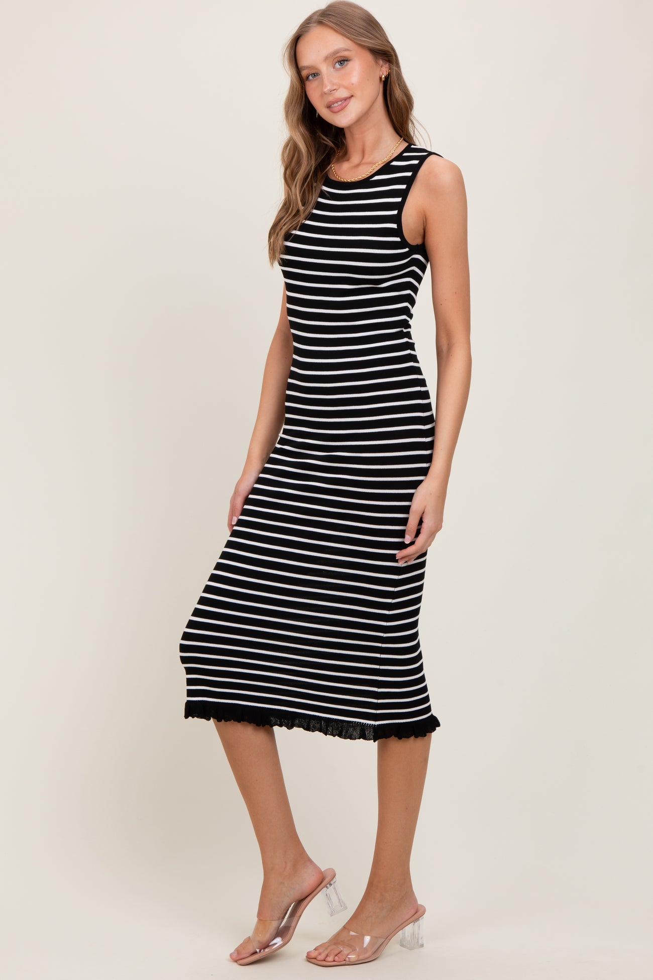 woman wearing a black and white striped sleeveless midi dress with a lace hem detail
