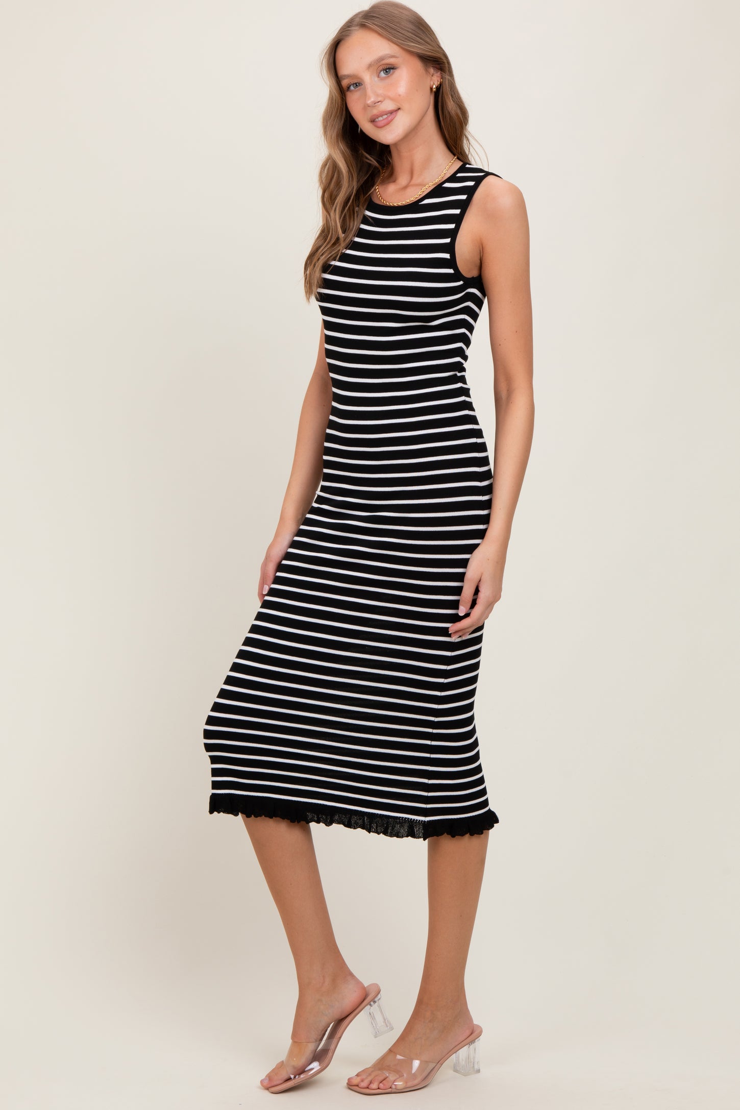 woman wearing a black and white striped sleeveless midi dress with a lace hem detail