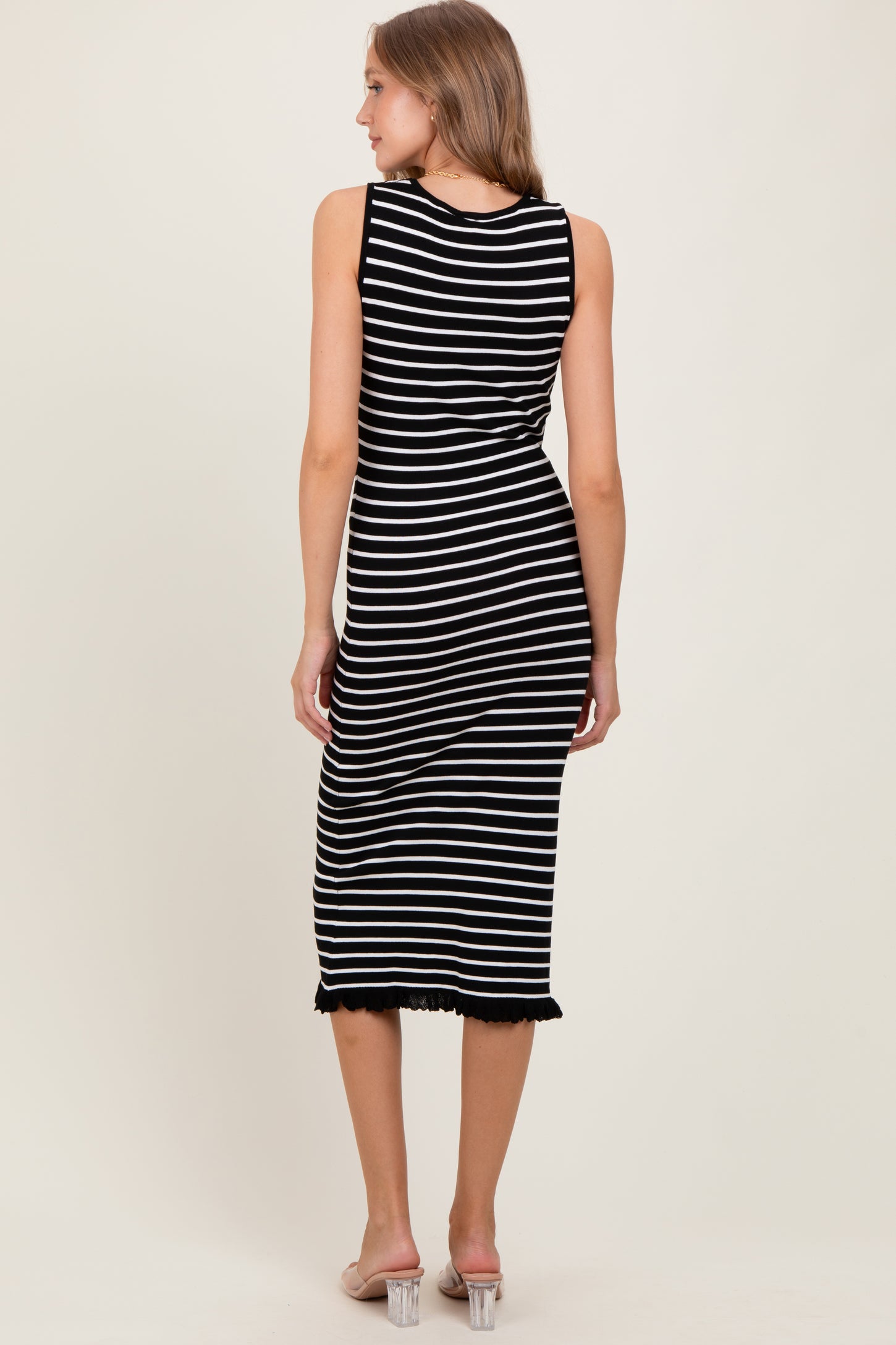 woman wearing a black and white striped midi dress with a ribbed texture and frayed hem