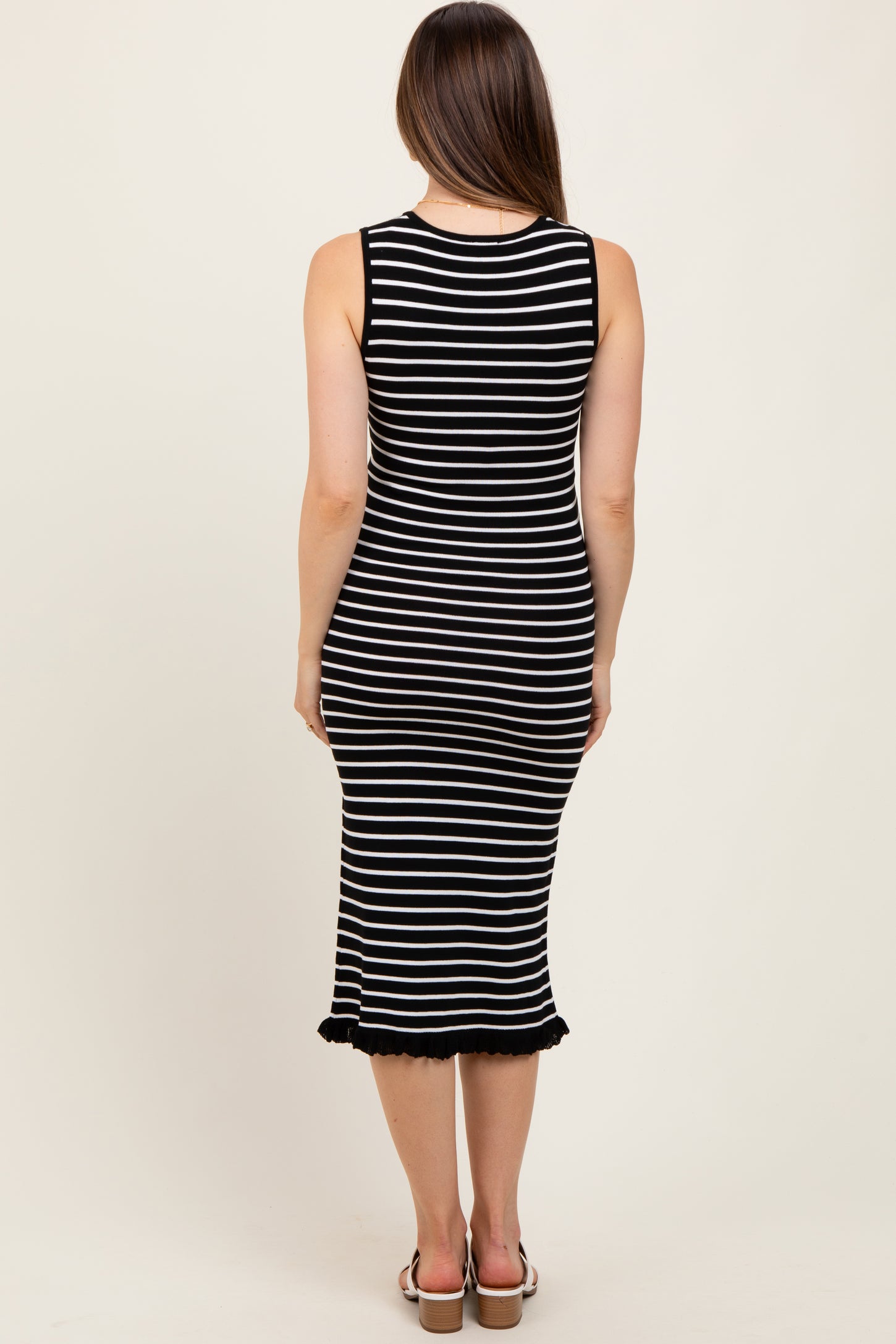 woman wearing a black and white striped maternity midi dress with a fitted silhouette and ruffle hem