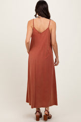 woman wearing a rust-colored sleeveless maxi dress with a v-back and adjustable straps