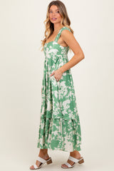 woman wearing a green floral maxi dress with pockets and tiered hem
