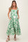 woman wearing a green floral print maternity dress with a tiered skirt and pockets