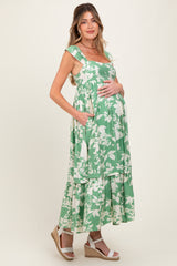 woman wearing a green floral maternity maxi dress with pockets and a visible baby bump