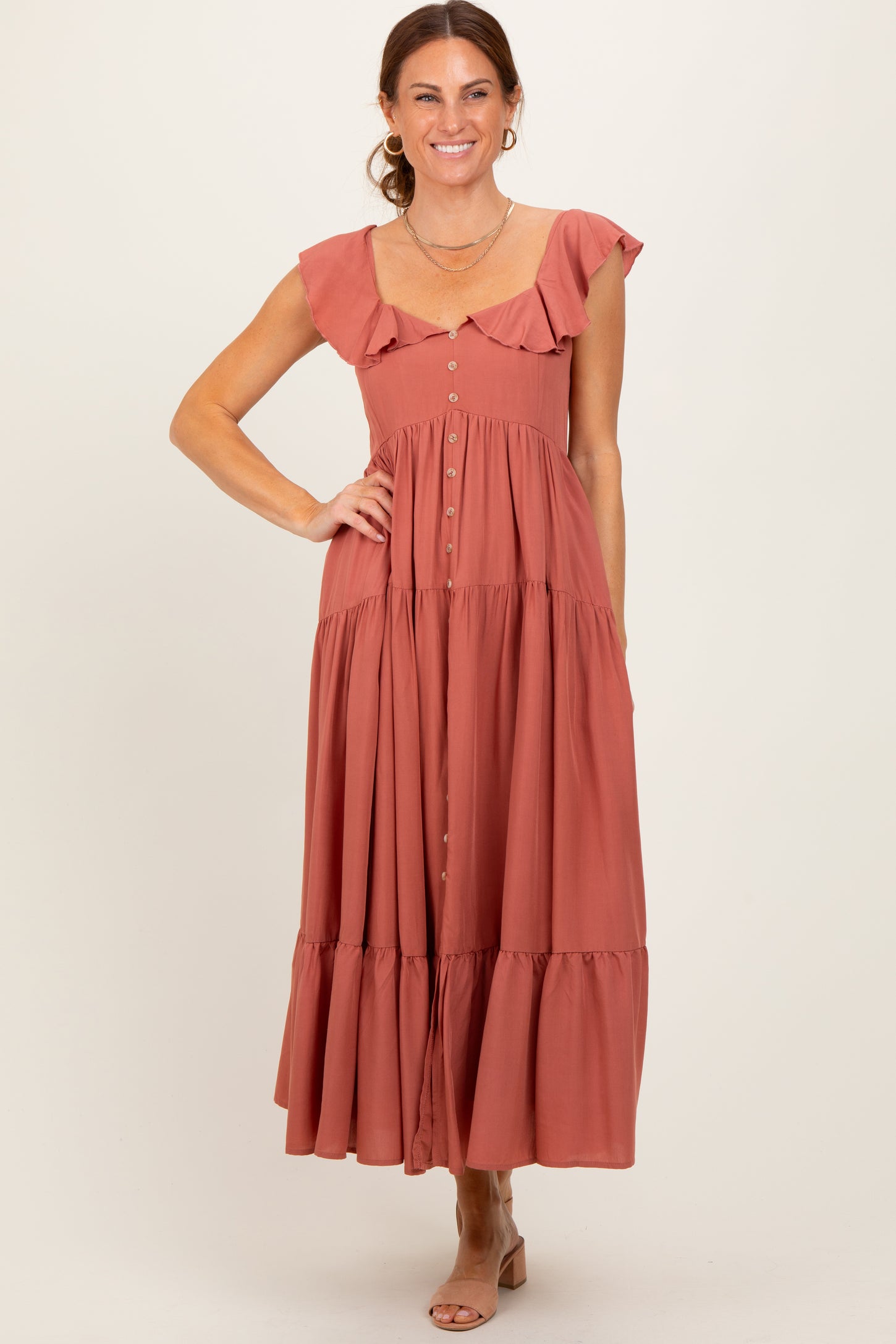 woman wearing a dusty rose tiered maxi dress with flutter sleeves and buttons down the front