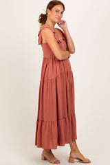 woman wearing a rust color maxi dress with ruffle straps and tiered hem, standing with hands on hips
