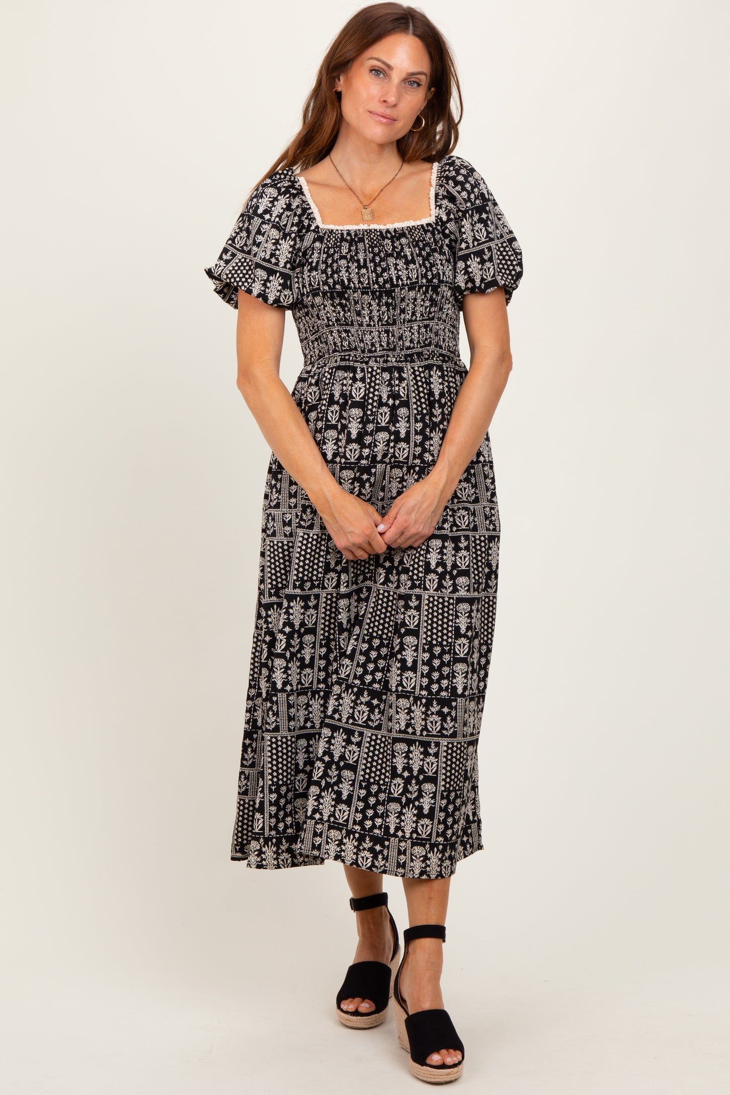 woman wearing a black and white patterned maxi dress with puff sleeves and a smocked bodice