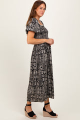 woman wearing a black and white patterned maxi dress with puff sleeves and a smocked bodice, standing sideways in wedges