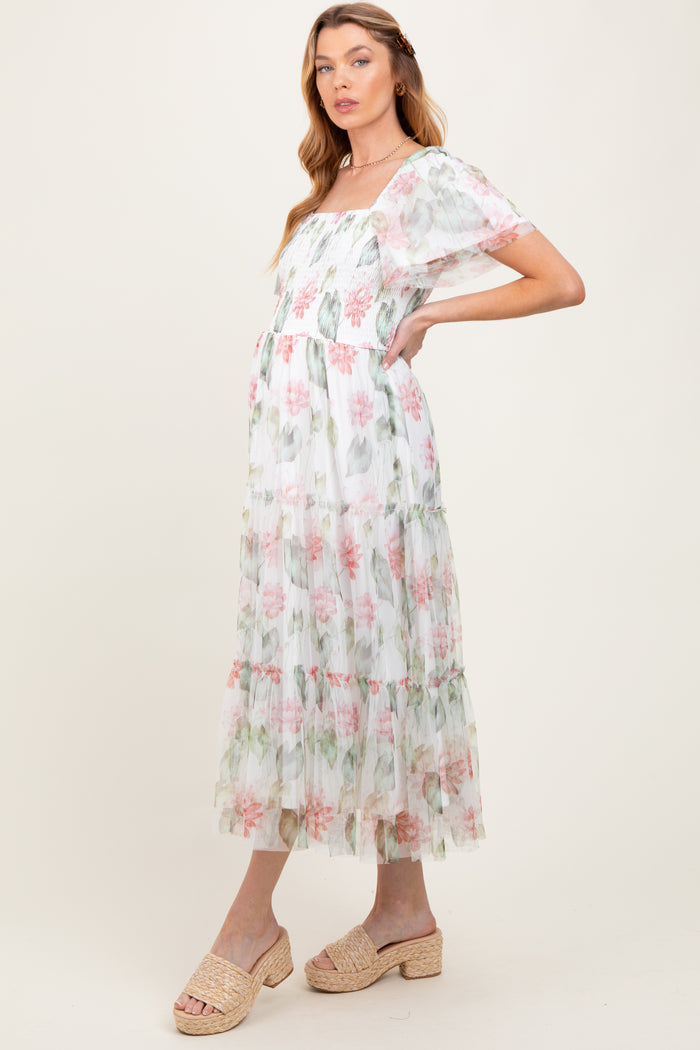 woman wearing a floral print maternity maxi dress with tiered ruffles and short sheer sleeves, showcasing her baby bump