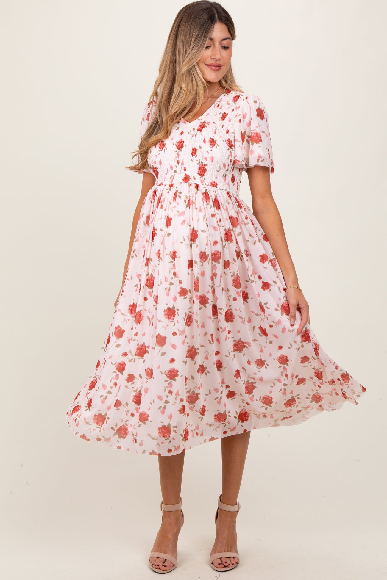 woman wearing a floral smocked maternity dress with short sleeves and a flowing skirt, highlighting her baby bump