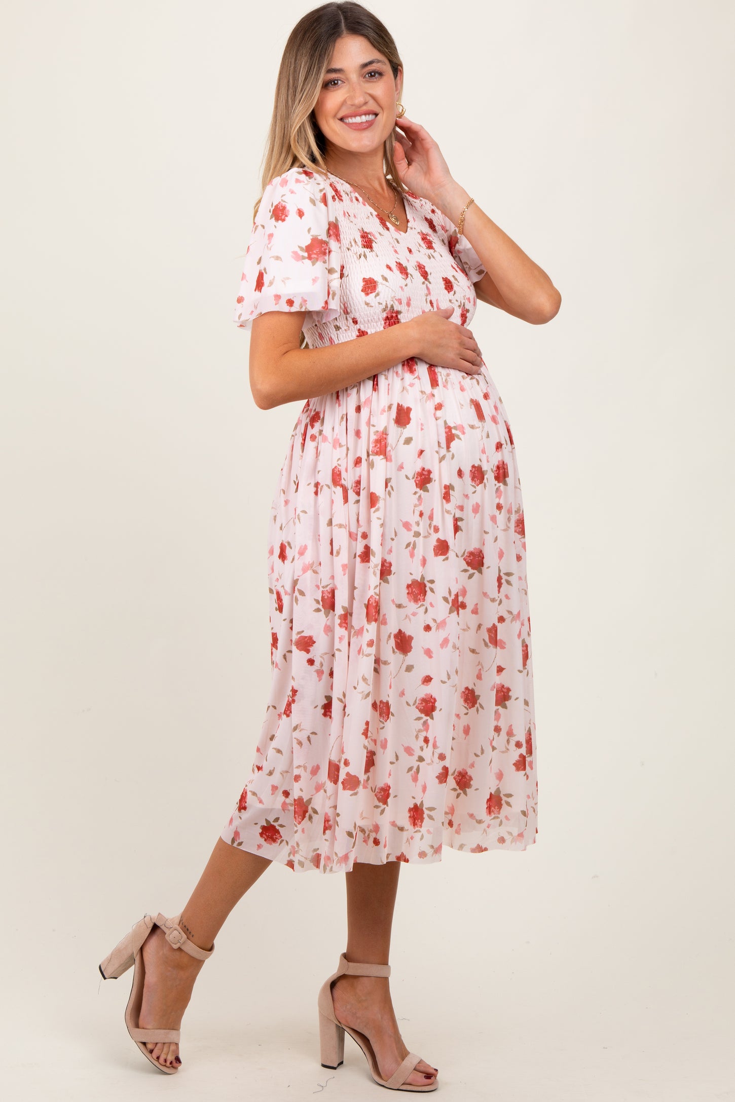 woman wearing a floral maternity dress with puff sleeves and a fitted bodice, showing her baby bump