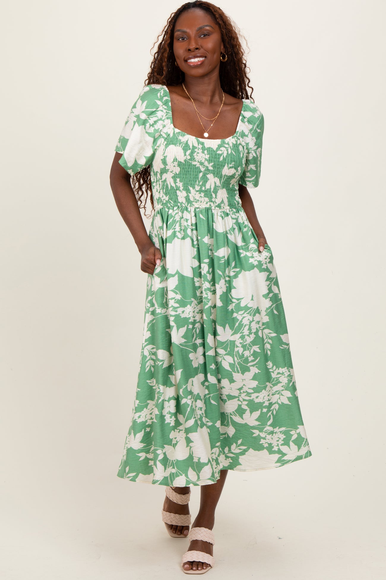 woman wearing a green floral smocked maxi dress with short puff sleeves and pockets