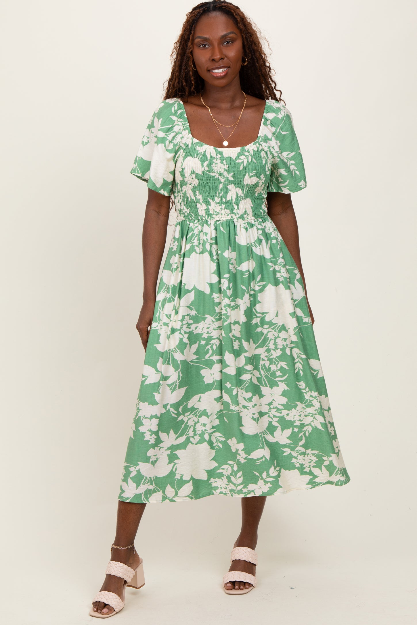 woman wearing a green floral midi dress with puff sleeves and a smocked bodice