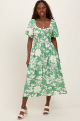 woman wearing a green floral midi dress with puff sleeves and a smocked bodice