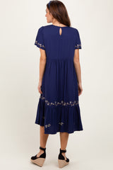 woman wearing a navy blue embroidered tiered midi dress with short sleeves and a keyhole back detail