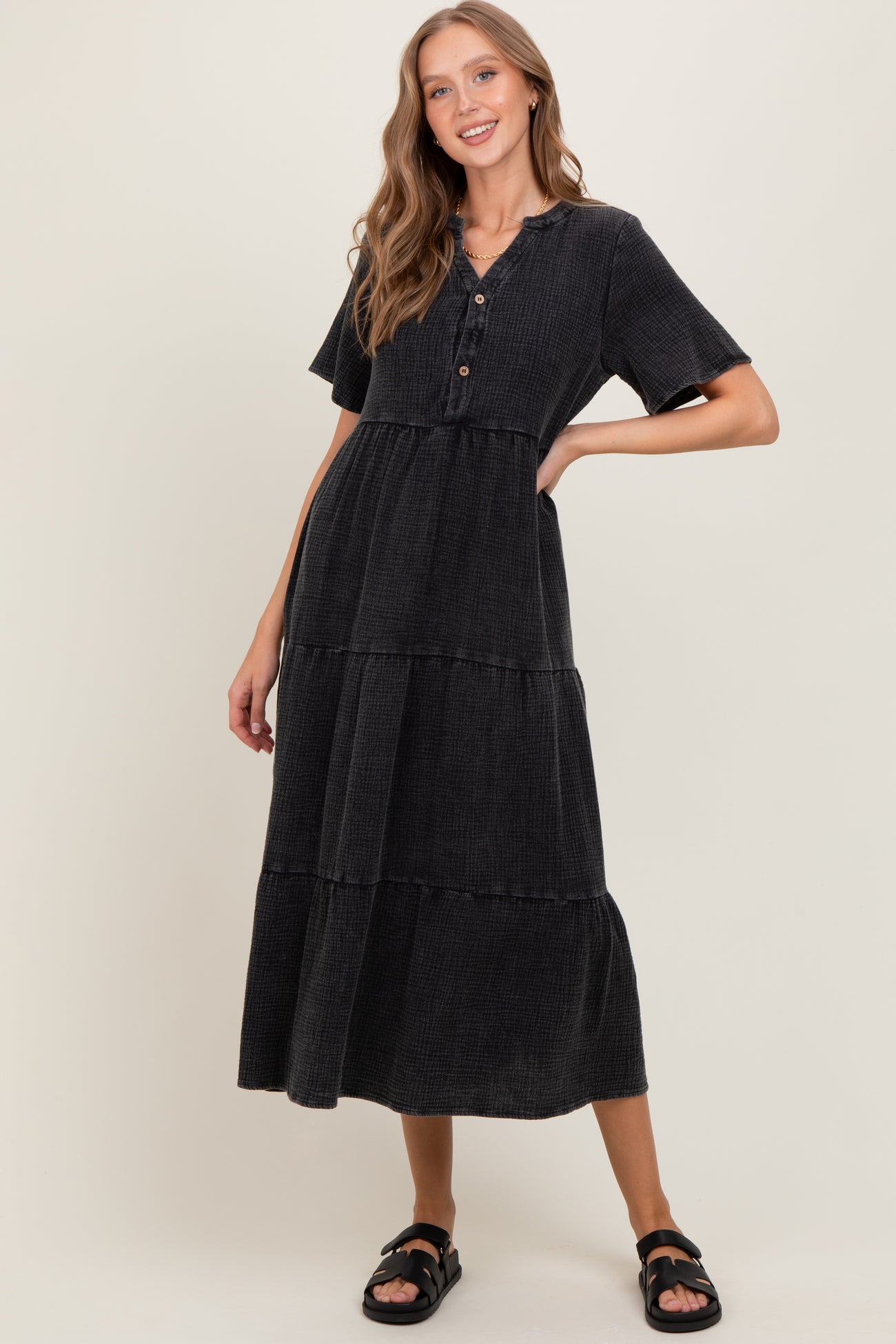 woman wearing a black tiered midi dress with short sleeves and buttons at the neckline