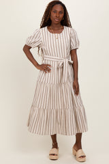 woman wearing a striped midi dress with puff sleeves and a tie belt, standing on a light background