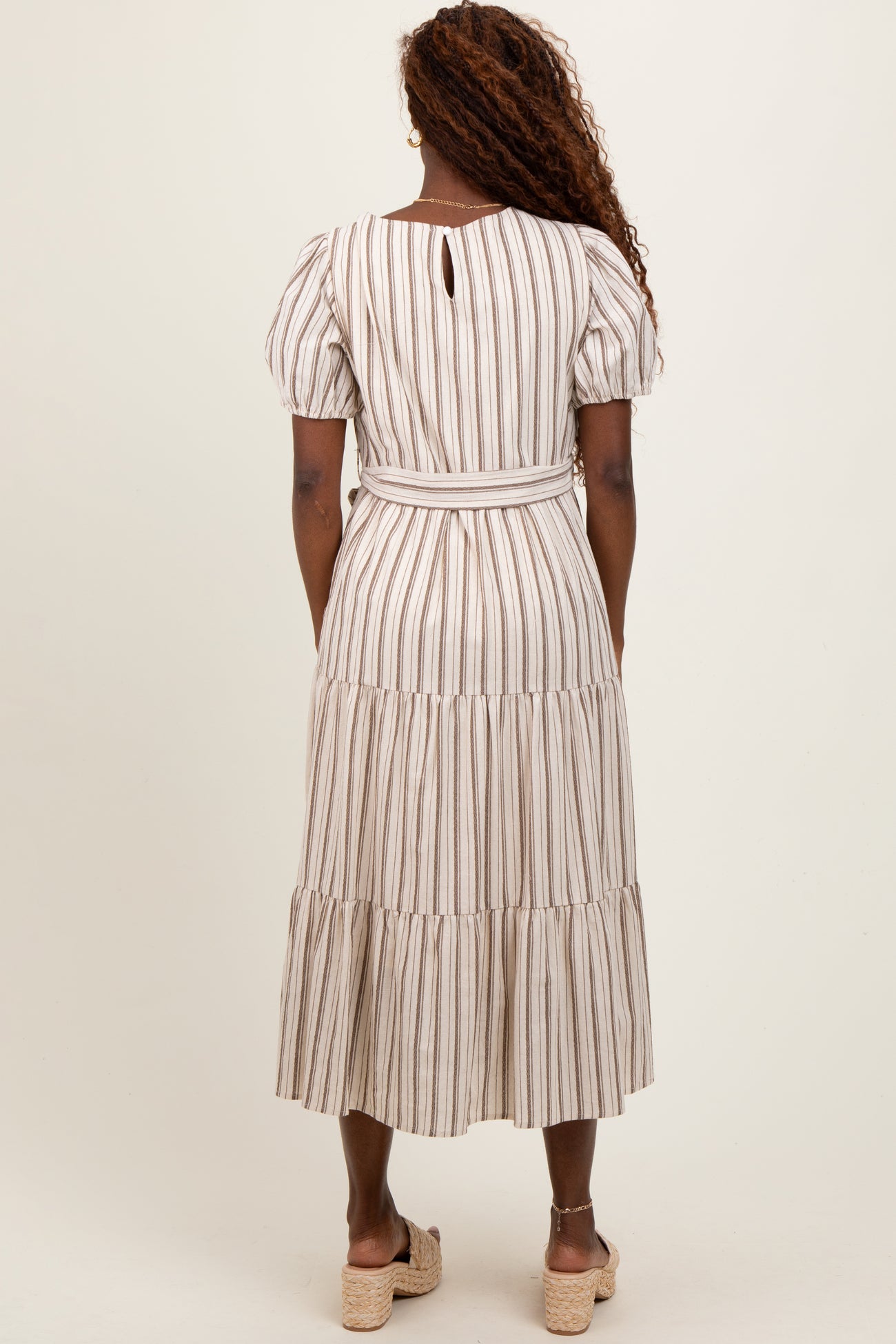 woman wearing a striped midi dress with puff sleeves and a belted waist, shown from the back