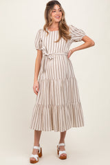 woman wearing a striped maternity dress with puff sleeves and a tie waist, showing her baby bump