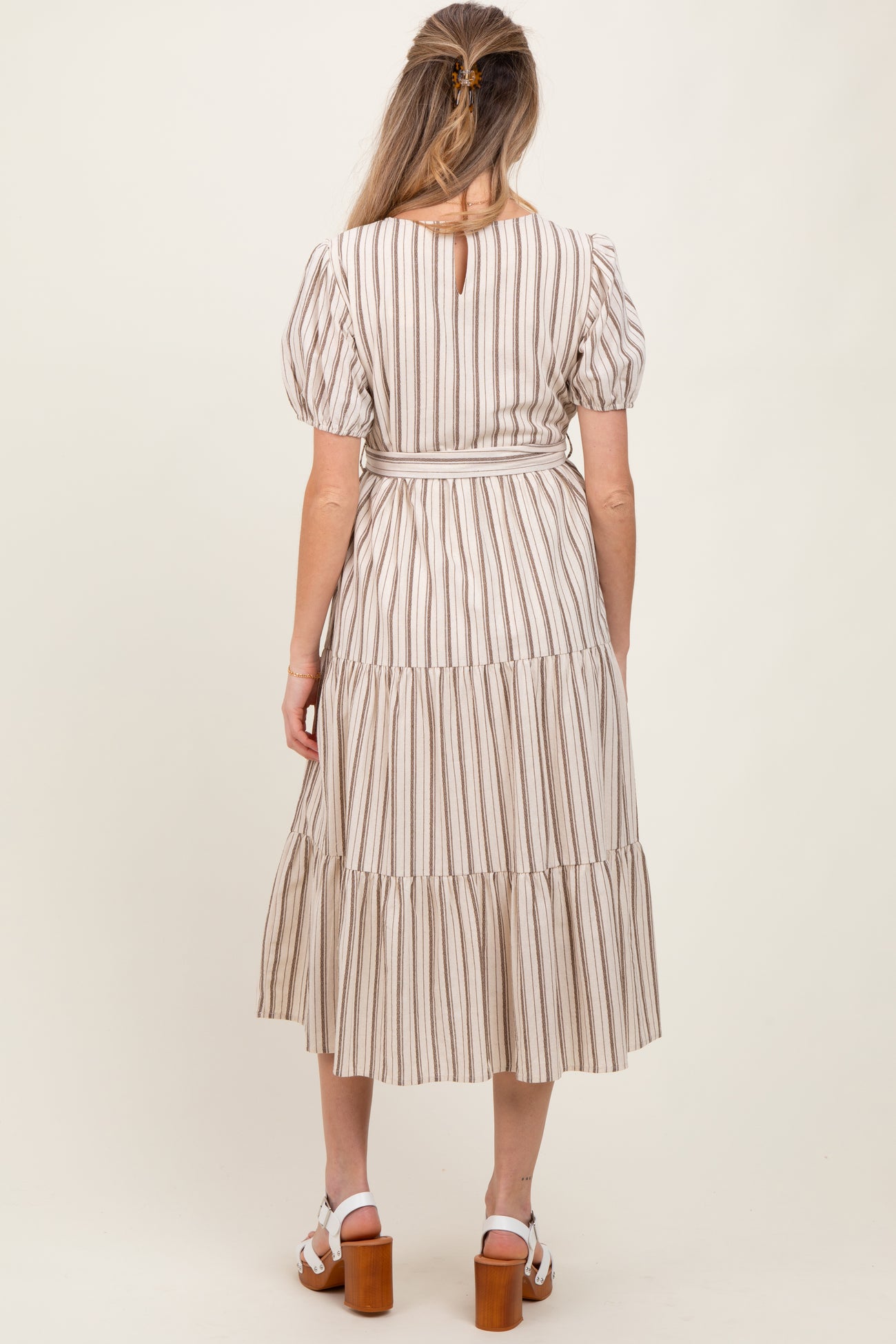 woman wearing a striped maternity maxi dress with puff sleeves and tiered skirt, showing a baby bump from the back